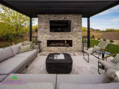 Custom backyard design with natural stone fireplace, metal fencing and outdoor seating area.