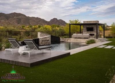 Custom backyard design with raised seating areas, pool and artificial turf.