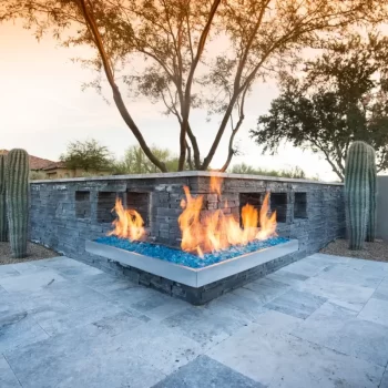Custom backyard design with angled fireplace, cacti and travertine tiles.