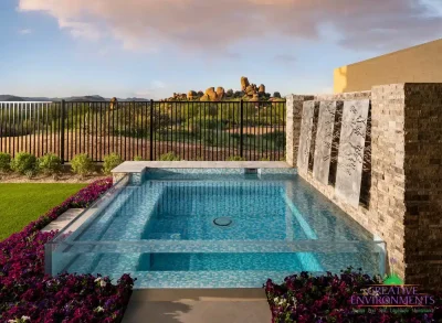 Custom backyard design with acrylic spa, metal statement piece and metal fencing.