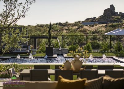 Custom backyard design with double water feature, multiple seating areas and bubblers in black pool.