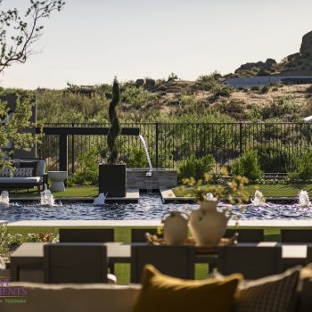 Custom backyard design with double water feature, multiple seating areas and bubblers in black pool.