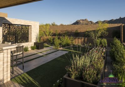 Custom backyard design with garden, custom metal cutouts and multiple seating areas under shade structure.