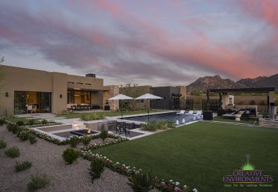 Custom backyard design with artificial turf, organized planting and shade structure.