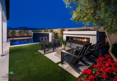 Custom backyard design with deco-tile fireplace, black water wall into pool and artificial turf.