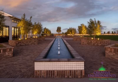 Custom community amenities with water feature, large brick planters and uplighting.