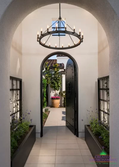 Unique front entry way with chandelier, metal trellis and arched door/doorway.
