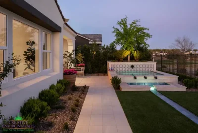 Custom backyard design with natural stone walkway, organized planting and a deco-tile spa that feeds into a metal scupper water feature.