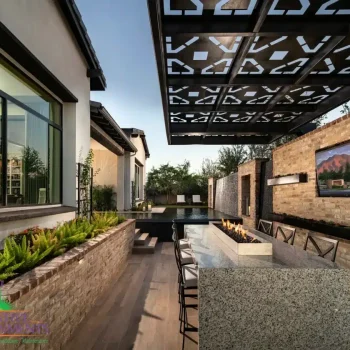 Custom backyard design with cantilevered shade structure with metal cutouts, outdoor TV and fire table.