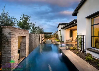 Custom backyard design with metal trellis and unique shaped, zero-edge pool.