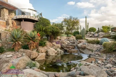 Front yard design with natural stone water fall, desert plants and small pool of water.