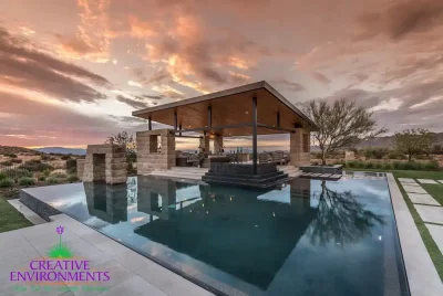 Custom backyard design with blue, lautner-edge pool and angled shade structure with outdoor kitchen.