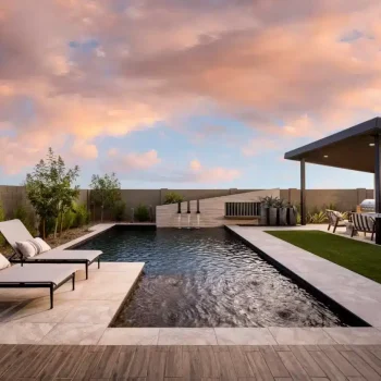 Custom backyard design with multiple seating areas and water feature into pool.