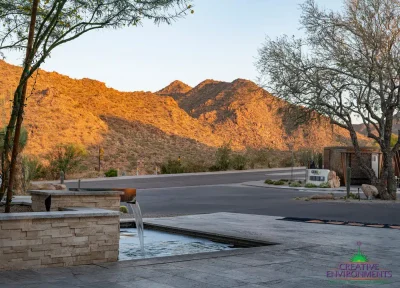 Custom community entrance with water feature, roundabout driveway and unique metal shade structure.