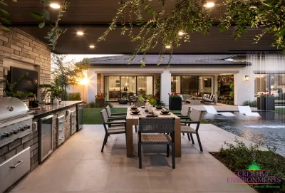 Custom backyard design with outdoor kitchen, pool with baja step and multiple seating areas.
