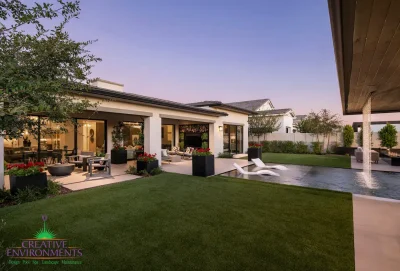 Custom backyard design with artificial turf, metal shade structure with rain curtain water feature and large metal planters.