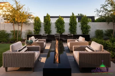 Custom backyard design with metal scupper water feature, fire pit and privacy hedges.