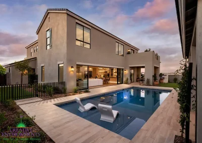 Custom backyard design with metal trellis, metal fencing and baja step in blue pool.