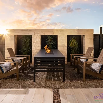 Custom backyard design with hanging plants, fire table and outdoor seating area.
