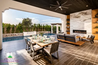 Custom backyard design with floor-to-ceiling marble fireplace, privacy hedges and multiple seating areas.
