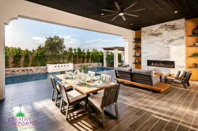 Custom backyard design with floor-to-ceiling marble fireplace, privacy hedges and multiple seating areas.