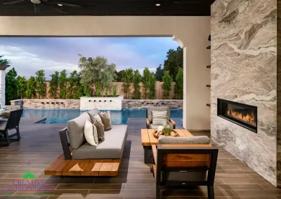 Custom backyard design with marble fireplace, metal water scupper feature and privacy hedges.