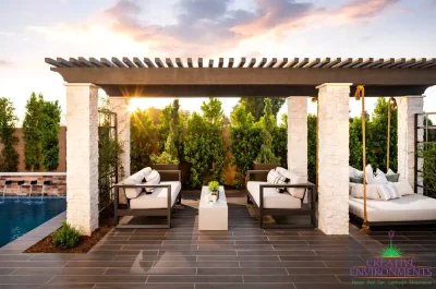Custom backyard design with slatted shade structure, hanging daybed and privacy hedges.