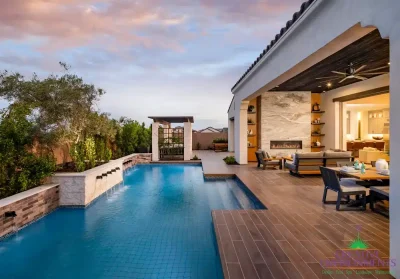 Custom backyard design with metal trellis, slatted shade structure and blue pool.