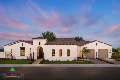 Custom front yard design with real grass, topiaries and mixed material driveway.