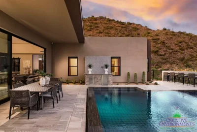 Custom backyard design with outdoor bar with deco-tile backsplash, multiple seating areas and pool.