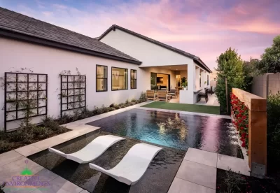 Custom backyard design with living wall, zero-edge pool with baja step and metal trellis.