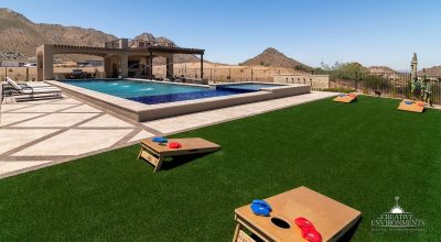 Custom backyard design with artificial turf, corn hole and metal scupper water feature.