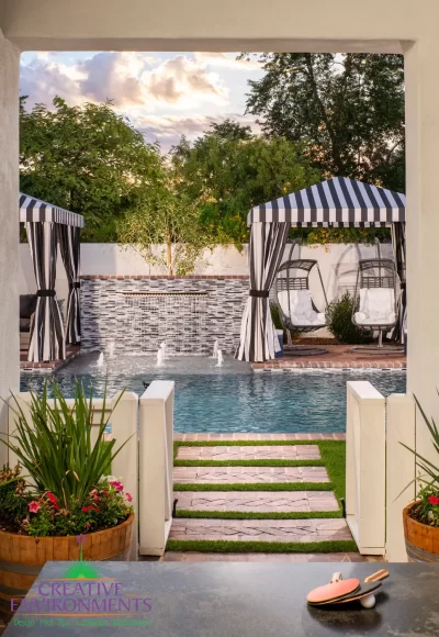 Custom backyard design with water bubbler, pool and multiple cabanas.