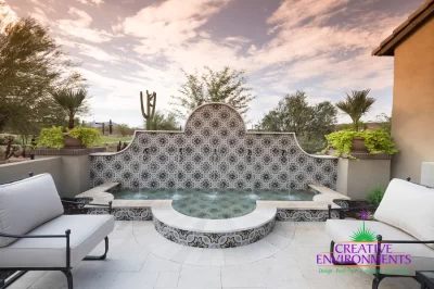 Custom backyard design with deco-tile water feature, Spanish design style and outdoor seating area.
