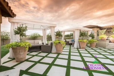 Custom backyard design with artificial turf pattern, cabanas and large planters.