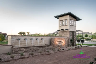 Custom community entrance with metal scupper water feature, unique entryway sign and cantilevered planters.