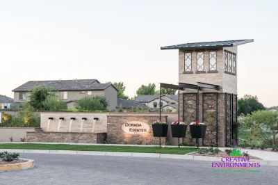 Custom community entrance with metal trellis, entryway sign and real grass.