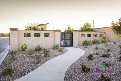 Custom community entrance with metal door, concrete pathway and organized planting.