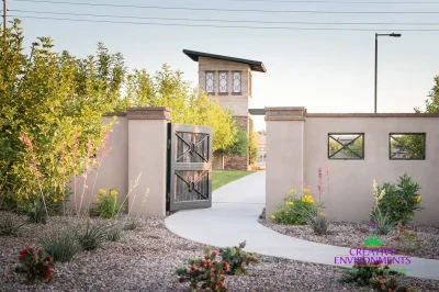 Custom community entrance with metal gate, concrete pathway and organized planting.