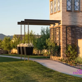 Custom community entrance with cantilevered planters, metal trellis and concrete pathway.