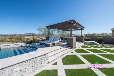 Custom backyard design with slatted shade structure, multiple seating areas and artificial turf pattern.