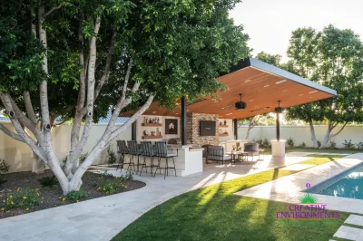 Custom backyard design with angled shade structure, real grass and blue pool.