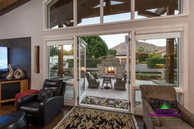 Custom indoor/outdoor design fusion with multiple seating areas, privacy hedges and outdoor fireplace.