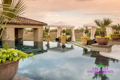 Custom backyard design with cabanas, zero-edge pool and large planters.