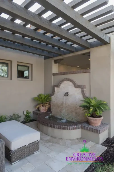 Custom backyard design with slatted shade structure, water feature and planters.