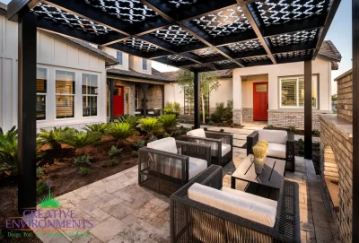 Custom backyard design with fireplace, metal shade structure with patterned roof and organized planting.