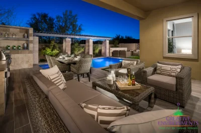 Custom backyard design with multiple seating areas, natural stone outdoor kitchen and blue pool.