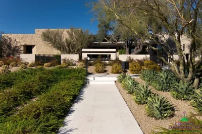 Custom entryway with organized planting, metal fencing and tree.