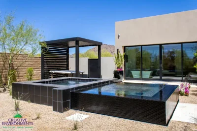 Custom backyard design with black raised spa, slatted metal shade structure and organized planting.