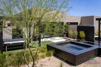 Custom backyard design with raised black spa, real grass and organized planting.